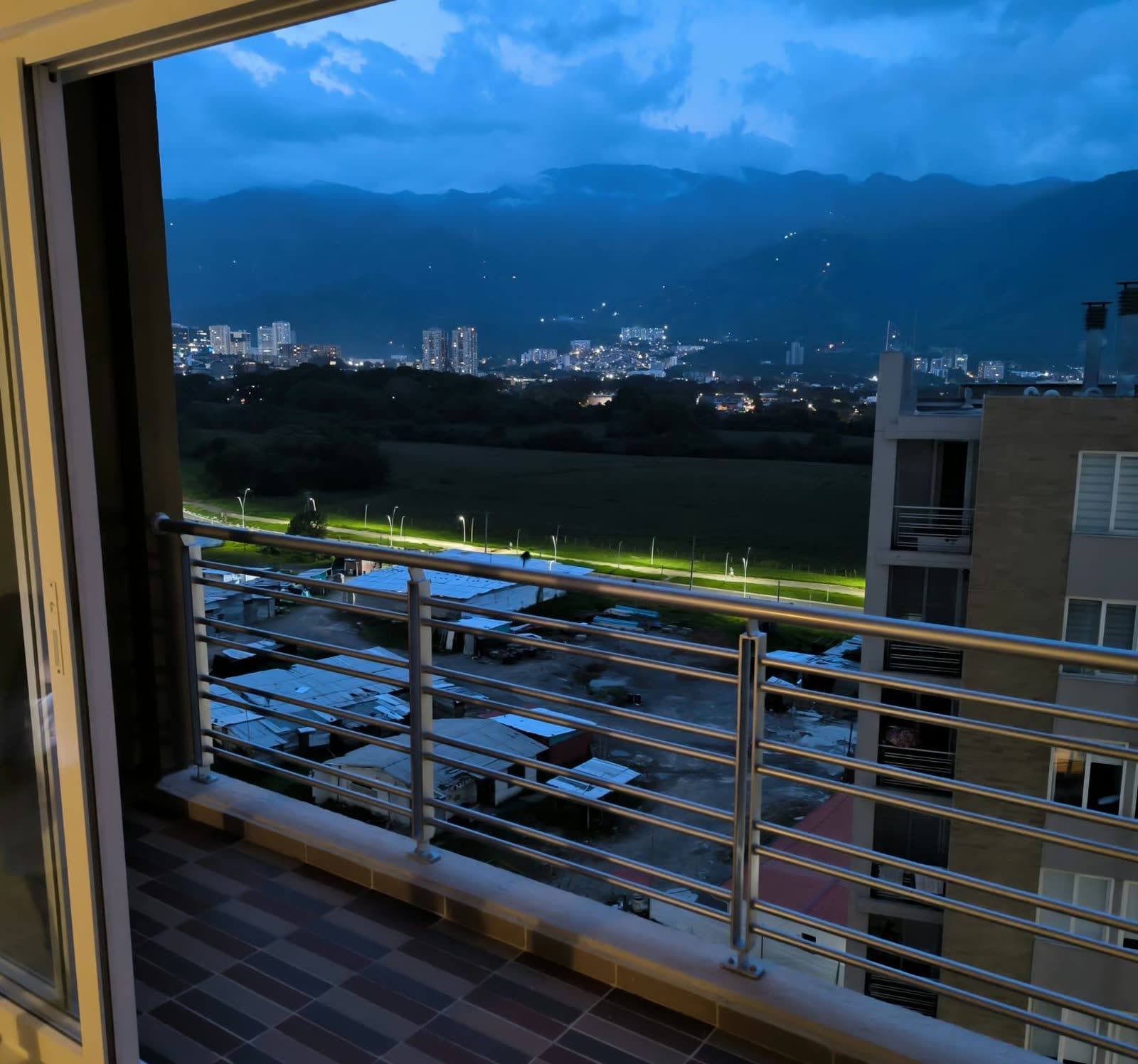 Vista desde el balcón al anochecer, con montañas y luces de la ciudad