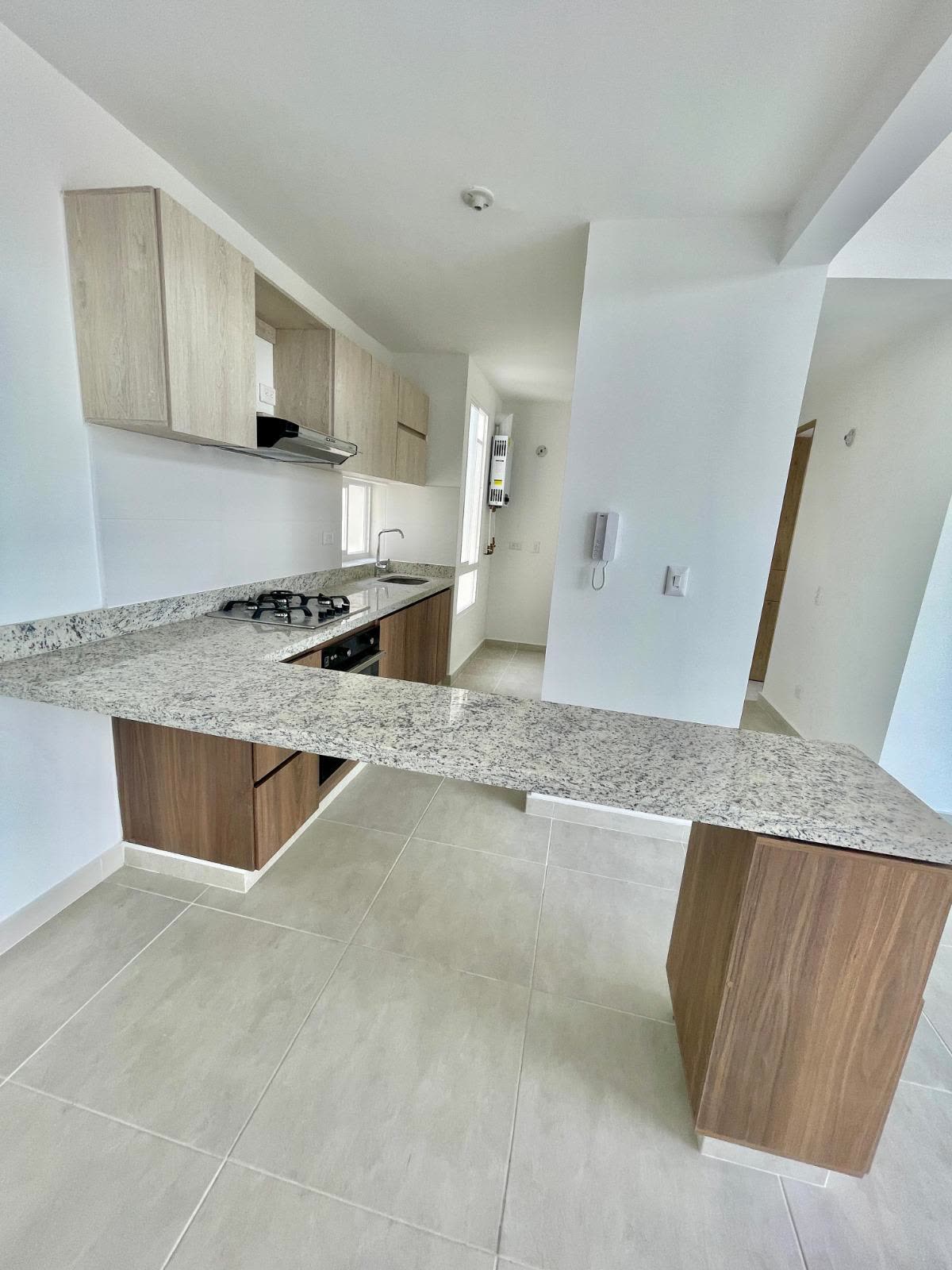 Cocina integral del apartamento, con barra y mesones en granito