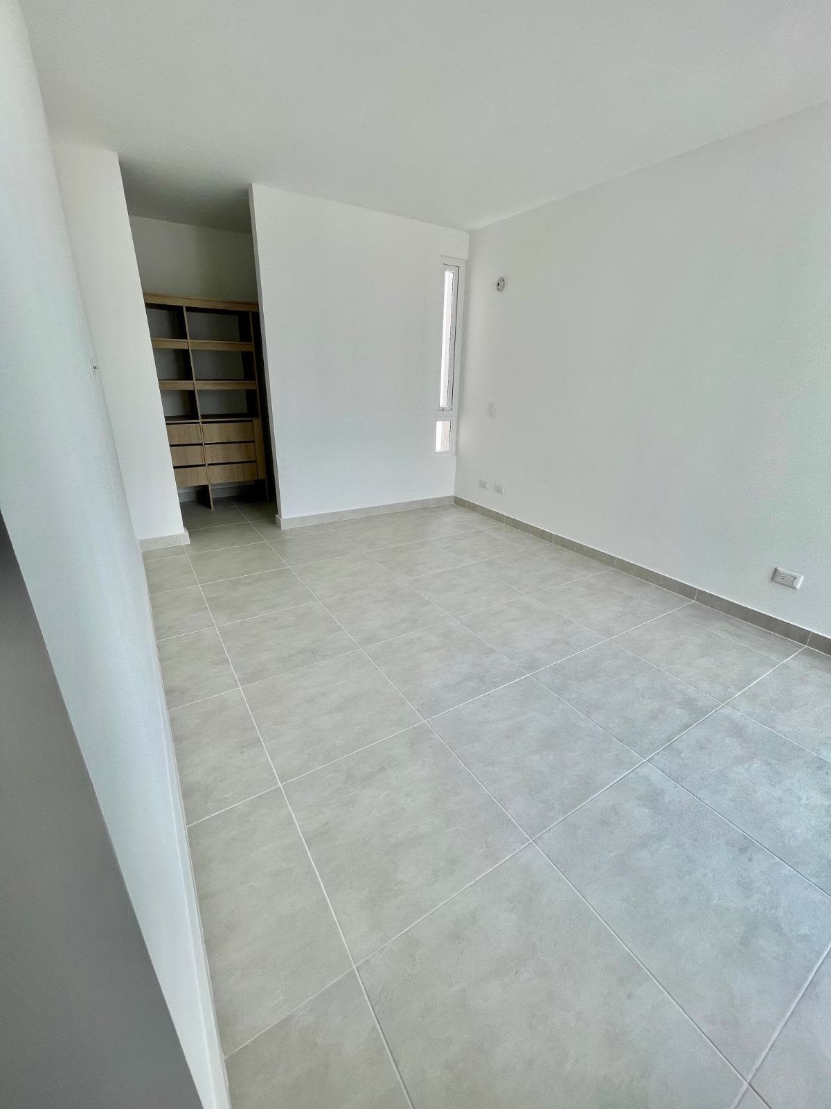 Habitación principal vacía con vestier visible y ventana angosta