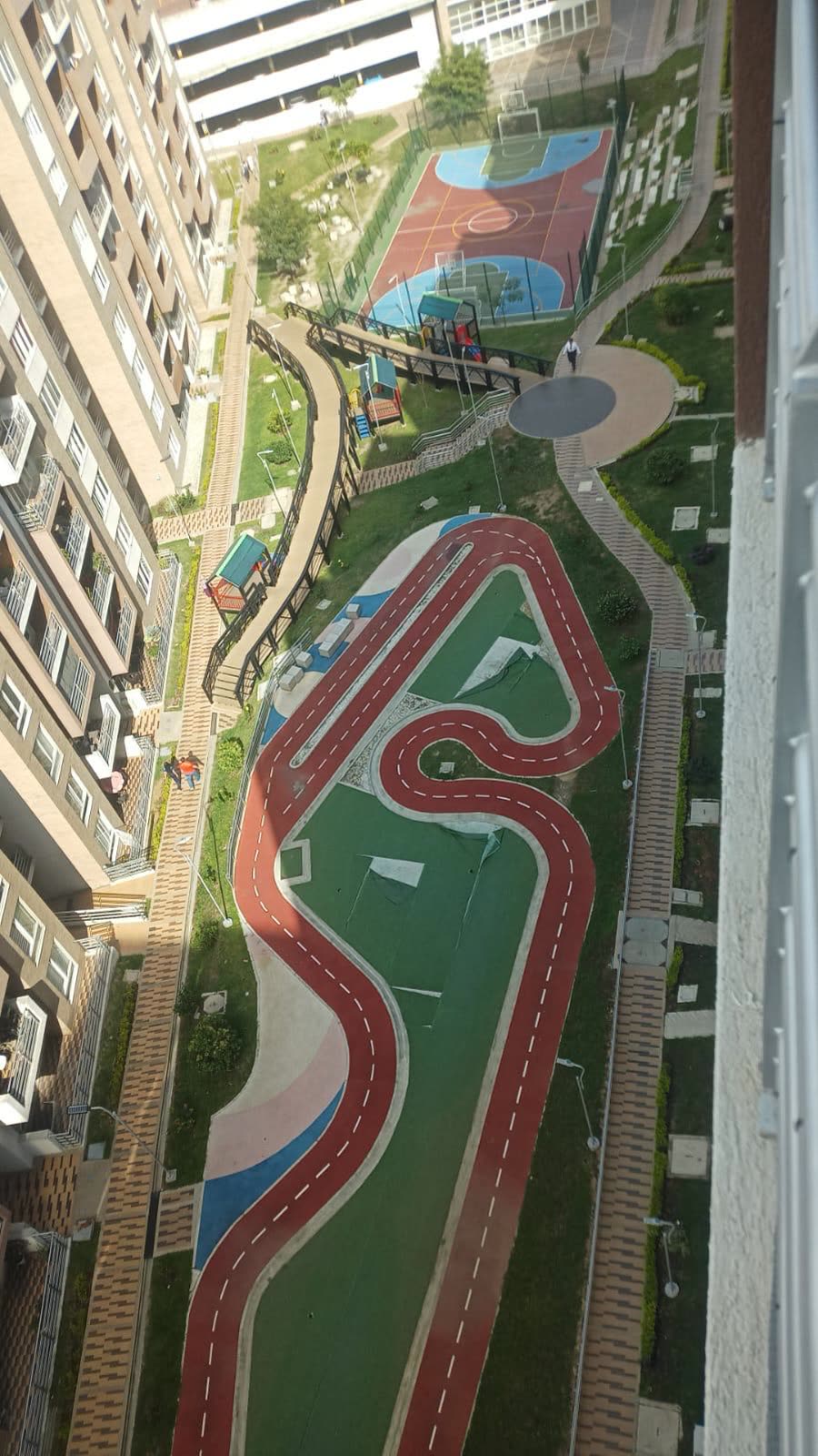 Vista aérea de las zonas comunes: pista, cancha múltiple, parque infantil y jardines